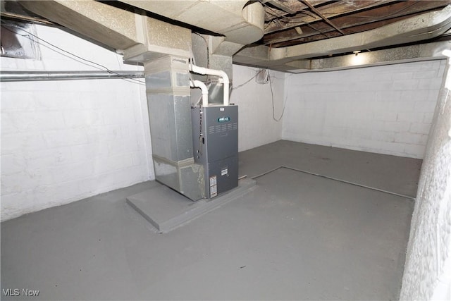 unfinished basement featuring concrete block wall and heating unit