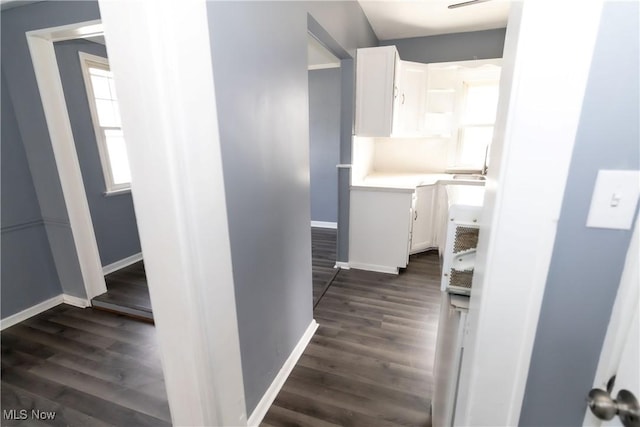 hallway featuring baseboards and dark wood finished floors