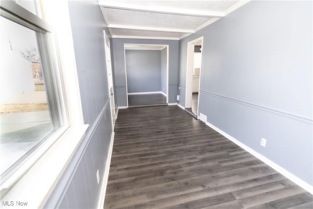 corridor featuring dark wood-style floors, baseboards, ornamental molding, and a wealth of natural light