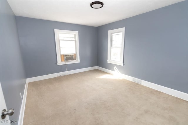 carpeted empty room featuring baseboards, visible vents, and cooling unit