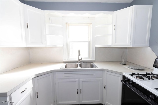 kitchen featuring a sink, white cabinets, light countertops, open shelves, and gas range oven