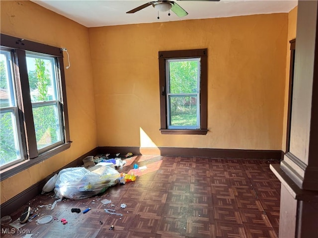 spare room featuring a healthy amount of sunlight, baseboards, and a ceiling fan