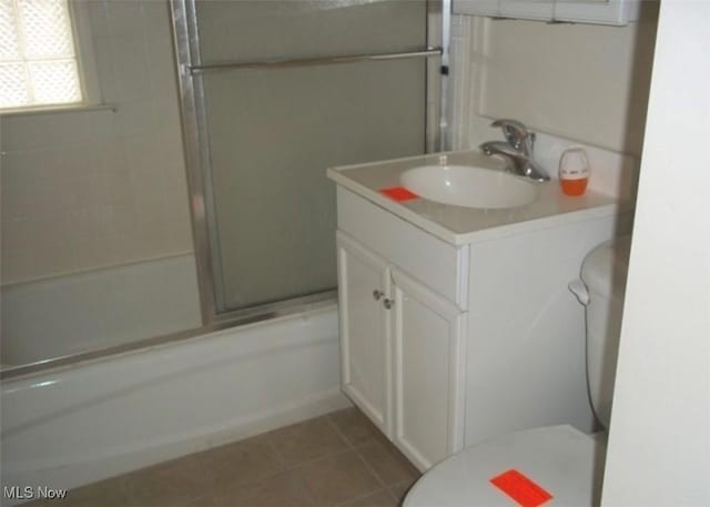 bathroom with toilet, shower / bath combination with glass door, vanity, and tile patterned floors