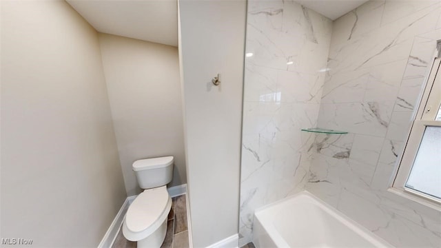 bathroom featuring bathing tub / shower combination, toilet, and baseboards