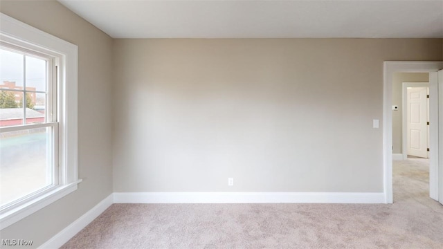 unfurnished room with baseboards and light colored carpet