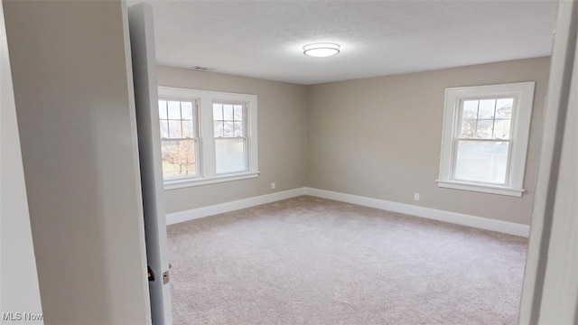 spare room with a healthy amount of sunlight, baseboards, and carpet floors