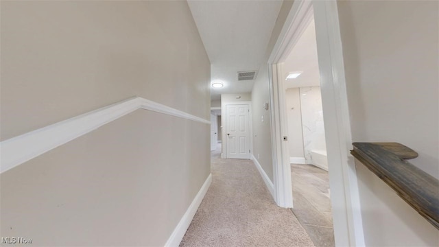 corridor featuring light colored carpet, visible vents, and baseboards