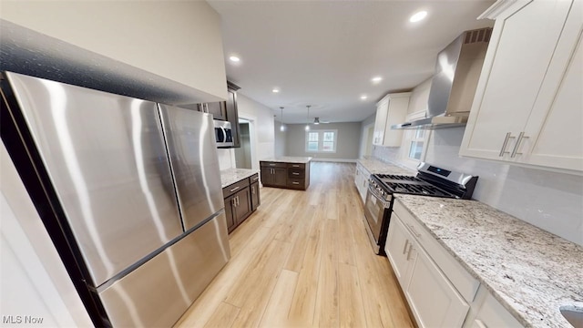 kitchen with white cabinets, wall chimney exhaust hood, light wood-style flooring, appliances with stainless steel finishes, and recessed lighting