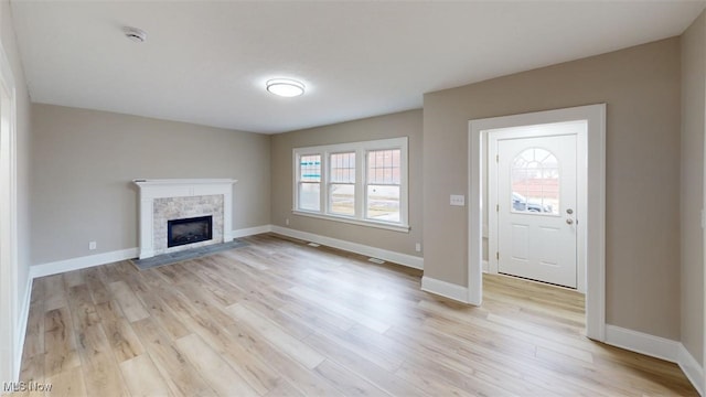 foyer entrance with light wood-style floors, a fireplace, and a wealth of natural light