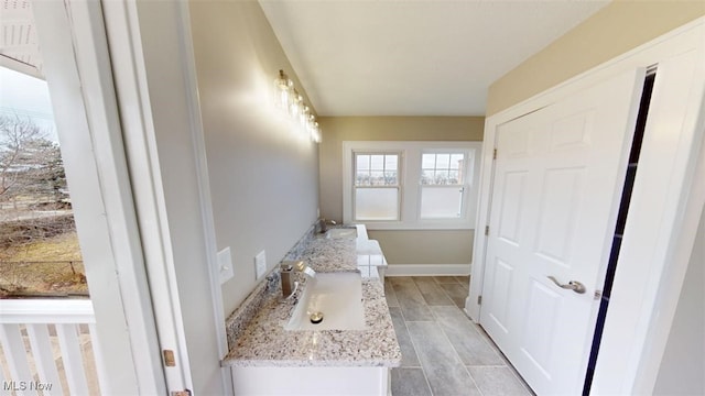 bathroom with wood finish floors, vanity, and baseboards