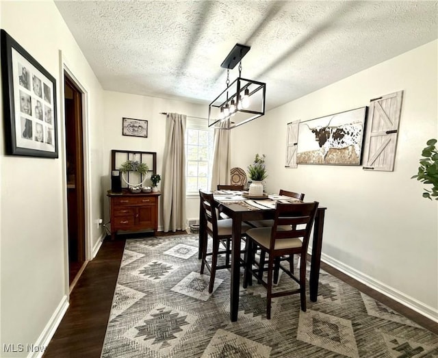 dining space featuring an inviting chandelier, a textured ceiling, baseboards, and dark wood-type flooring