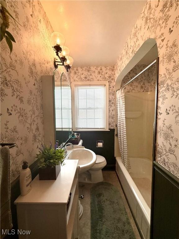 full bathroom featuring shower / bath combination with curtain, vanity, toilet, and wallpapered walls