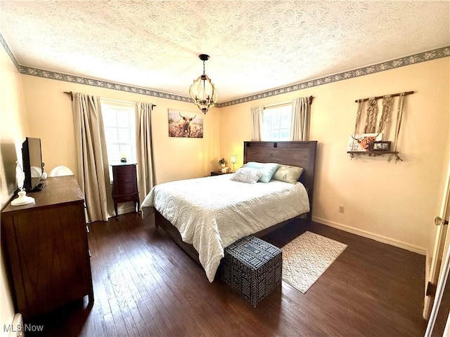 bedroom featuring a textured ceiling, dark wood-style flooring, an inviting chandelier, and baseboards