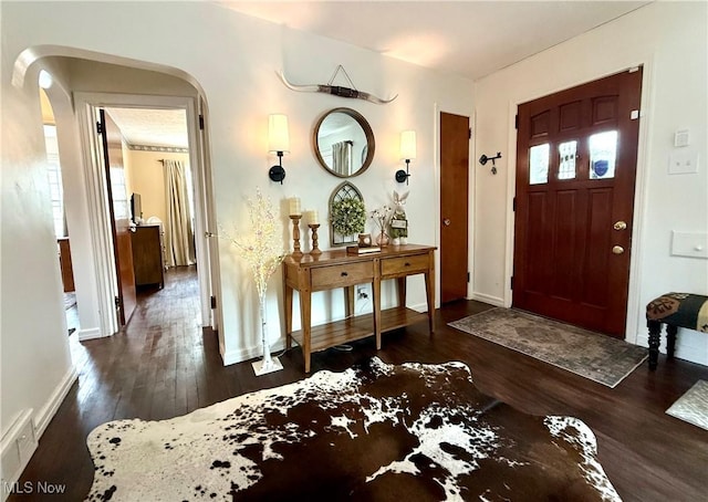 foyer featuring arched walkways, visible vents, baseboards, and wood finished floors