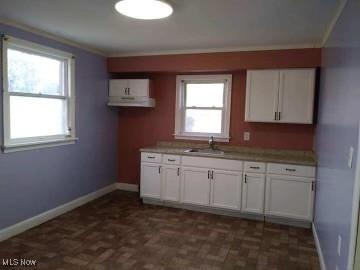 kitchen with baseboards, white cabinets, and a sink