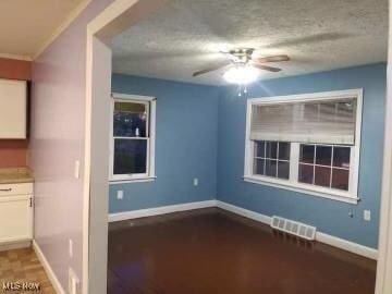 spare room featuring baseboards, a textured ceiling, visible vents, and a ceiling fan