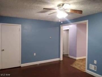 unfurnished room with ceiling fan, baseboards, and a textured ceiling