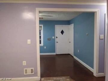 hallway with visible vents, baseboards, and wood finished floors