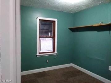 unfurnished room with a textured ceiling and baseboards