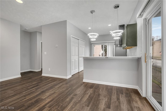 kitchen featuring dark wood-style floors, a peninsula, freestanding refrigerator, and baseboards