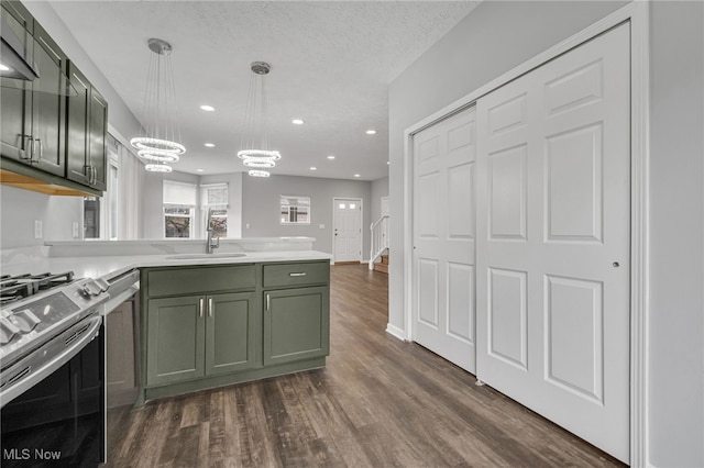 kitchen featuring dark wood-style flooring, a peninsula, green cabinets, a sink, and gas stove