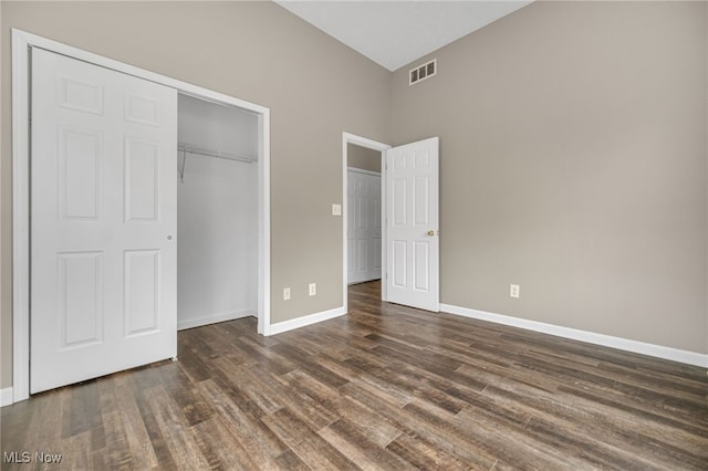 unfurnished bedroom featuring dark wood-type flooring, a closet, visible vents, and baseboards