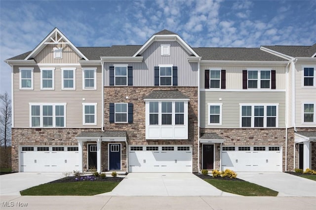 townhome / multi-family property featuring board and batten siding, concrete driveway, stone siding, and a garage