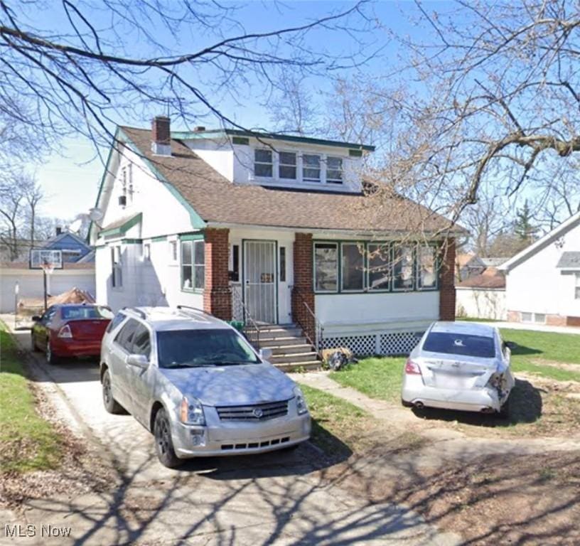 view of front of home featuring concrete driveway, brick siding, a chimney, and roof with shingles