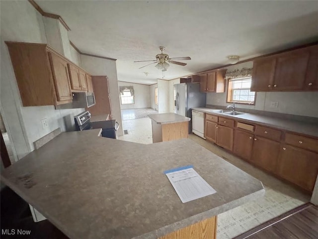 kitchen with ceiling fan, a kitchen island, appliances with stainless steel finishes, light countertops, and a sink