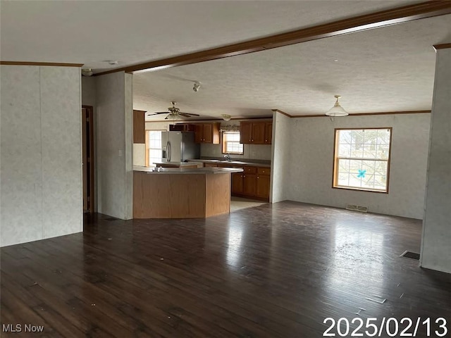 unfurnished living room featuring ornamental molding, visible vents, a sink, and wood finished floors