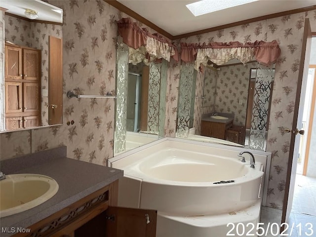 full bathroom with a skylight, a garden tub, vanity, and wallpapered walls