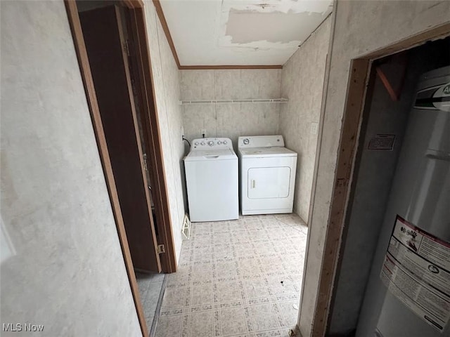 clothes washing area with laundry area, water heater, washer and clothes dryer, and light floors