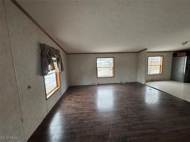 spare room with ornamental molding, visible vents, a textured ceiling, and hardwood / wood-style floors