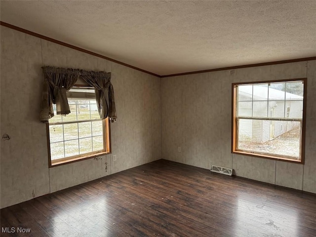 empty room featuring hardwood / wood-style flooring, visible vents, a textured ceiling, and ornamental molding