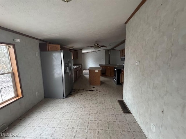 kitchen with stove, a kitchen island, visible vents, stainless steel refrigerator with ice dispenser, and light floors