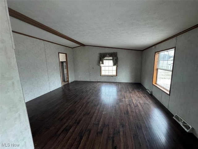 empty room with a textured ceiling, hardwood / wood-style flooring, visible vents, and crown molding