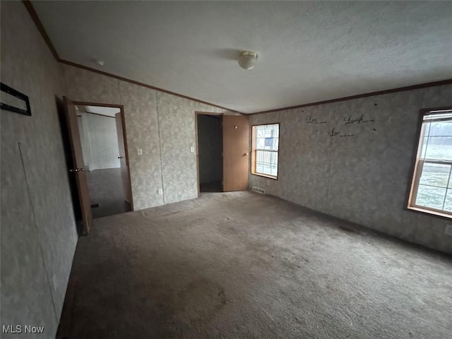 empty room with lofted ceiling, carpet, and crown molding