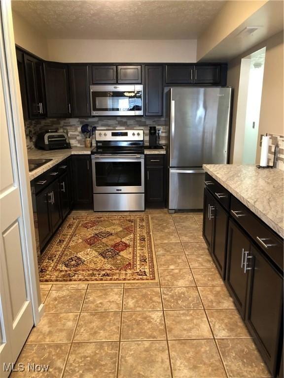 kitchen with light tile patterned floors, stainless steel appliances, decorative backsplash, and light countertops