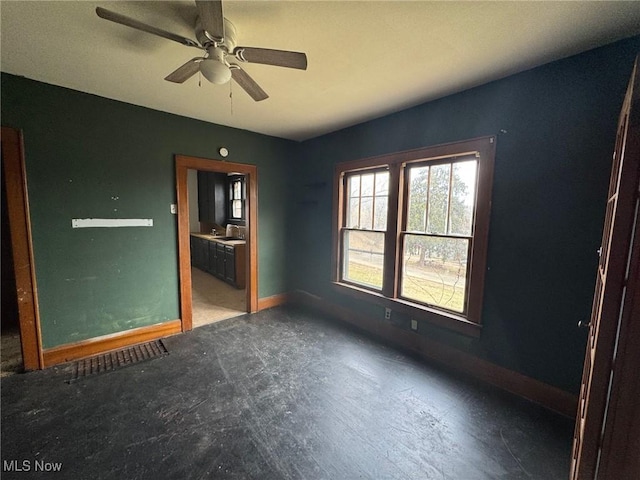 spare room with ceiling fan and baseboards