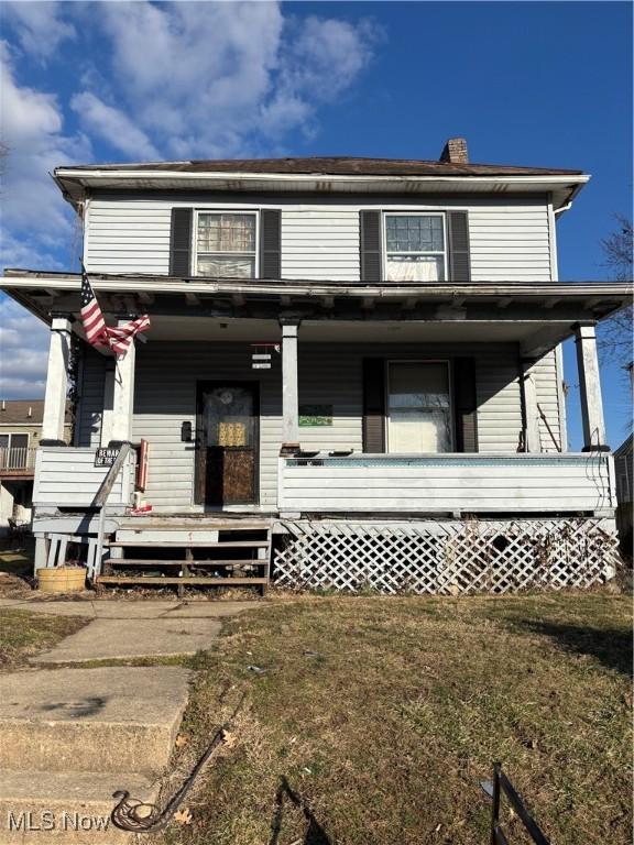 view of front of house with a chimney, a porch, and a front yard