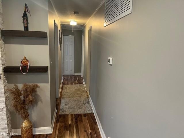 hallway featuring attic access, visible vents, baseboards, and wood finished floors