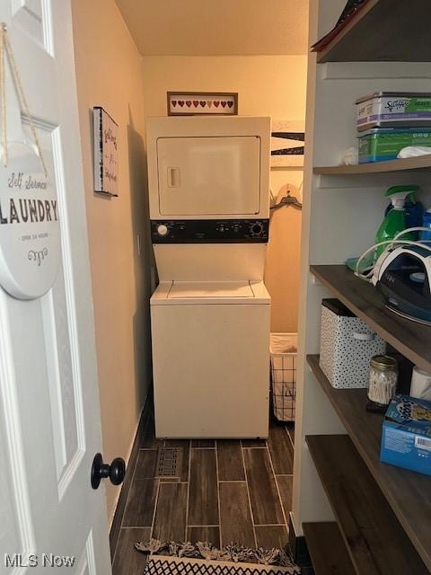 laundry room featuring laundry area, wood finish floors, and stacked washer / drying machine