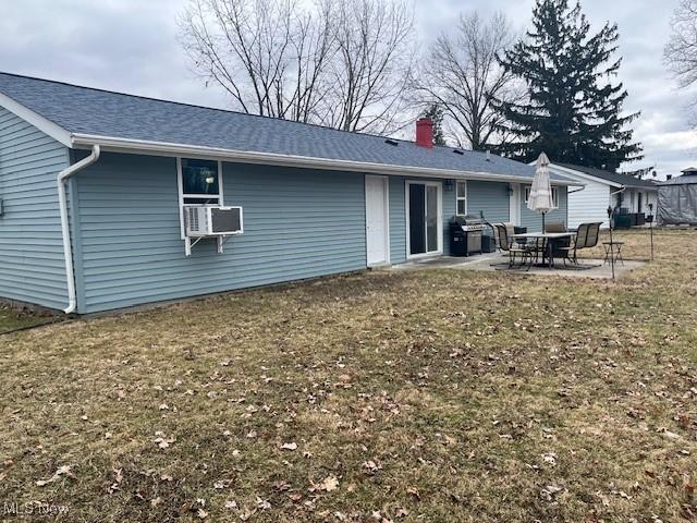 back of property with cooling unit, a patio area, a lawn, and a chimney