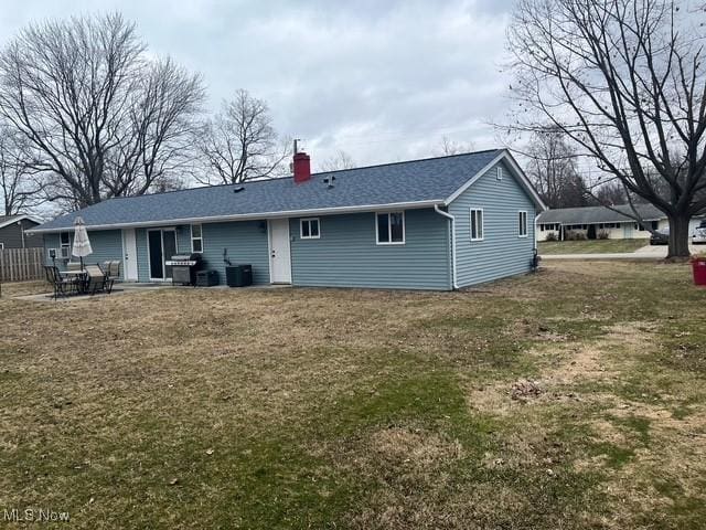 rear view of house featuring a yard, a chimney, a shingled roof, a patio area, and cooling unit