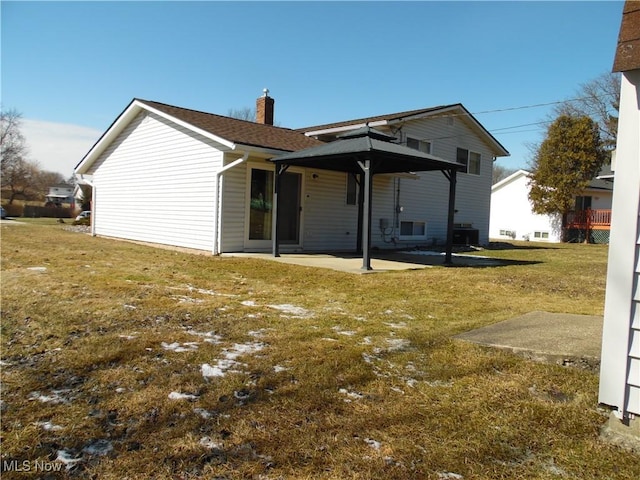 back of property with a patio, a chimney, and a lawn