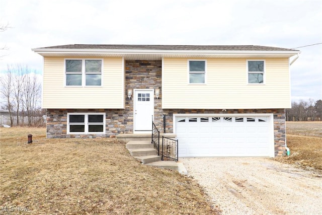 bi-level home with a garage, stone siding, and driveway