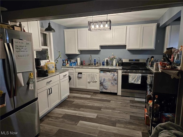 kitchen with stainless steel appliances, a sink, white cabinetry, light countertops, and dark wood-style floors