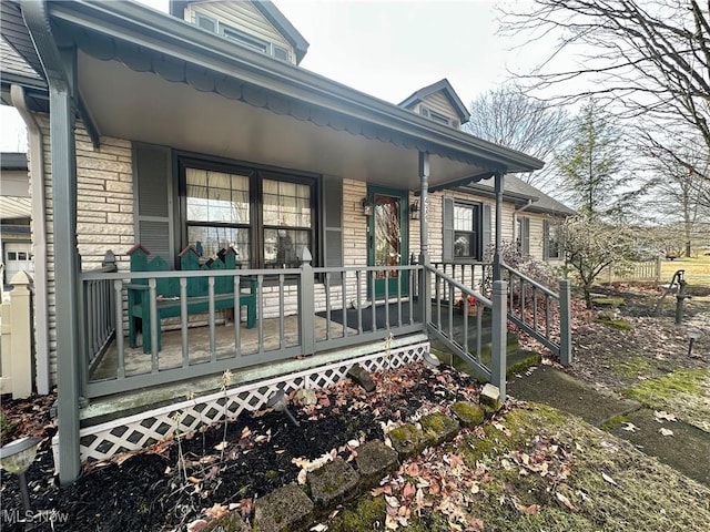 doorway to property featuring a porch and brick siding