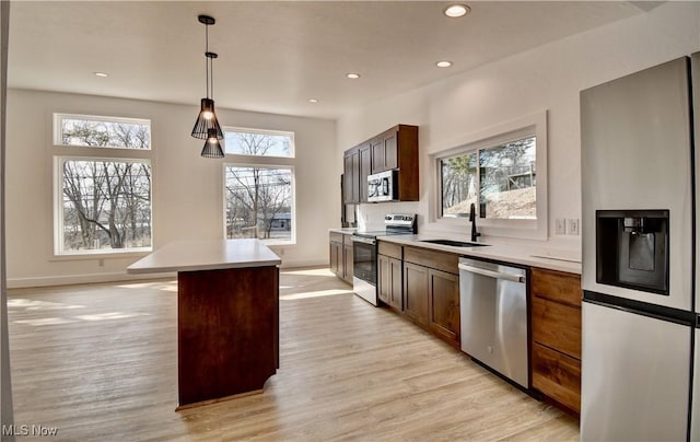 kitchen featuring light wood finished floors, stainless steel appliances, recessed lighting, light countertops, and a sink