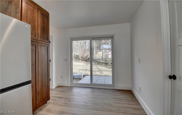 interior space with baseboards and light wood finished floors